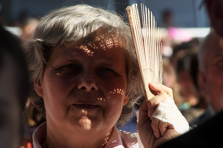 Женщина с веером укрывается от солнца на концерте Надежды Кадышевой. Фото Сергея Серебро